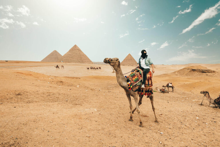 A woman riding a camel near the pyramids in Egypt